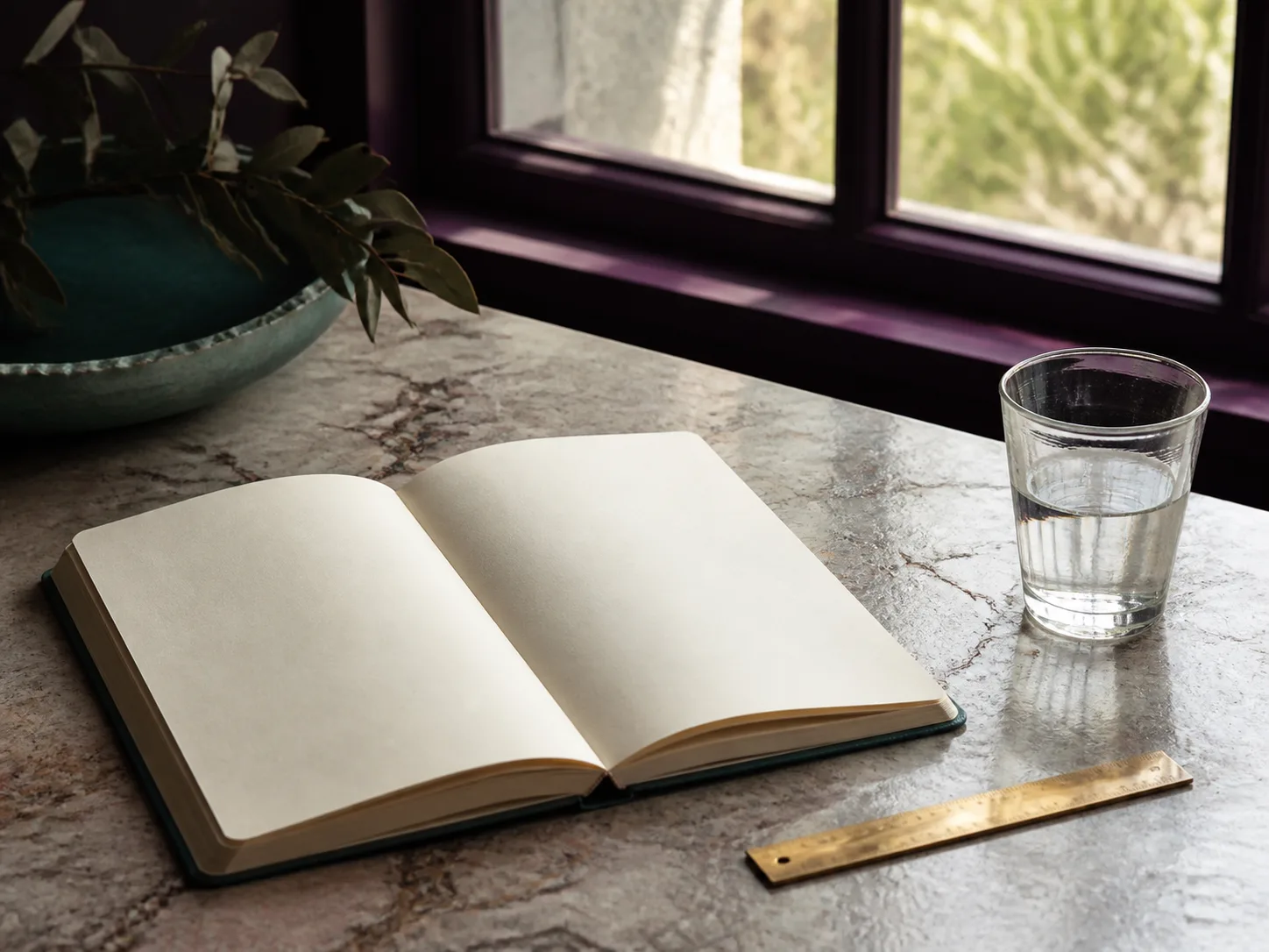 Carnet ouvert, verre d'eau et règle sur une table de pierre